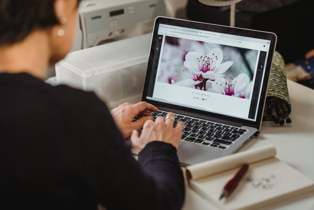 Adult browsing flower images on a laptop, suggesting remote work, digital engagement.